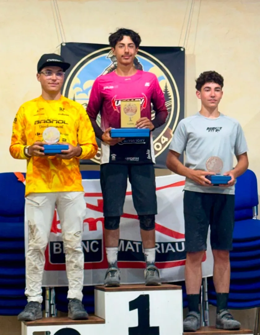 Victor Michaud, en maillot rose, sur la première marche du podium